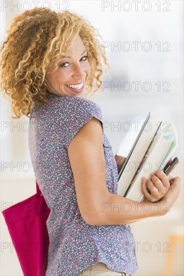 Young woman carrying books .