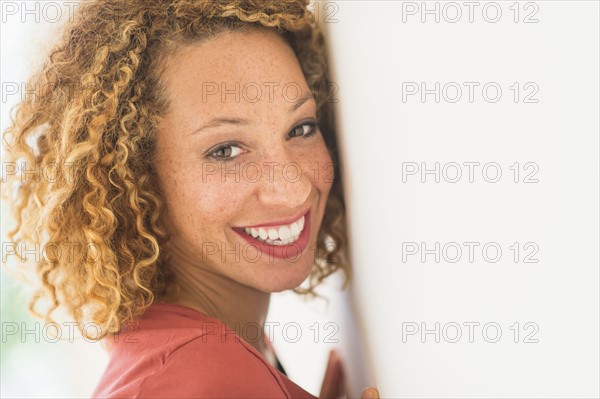 Portrait of smiling young woman near wall.