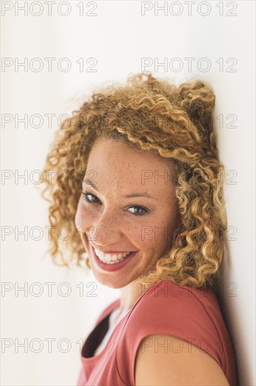 Portrait of smiling young woman near wall.