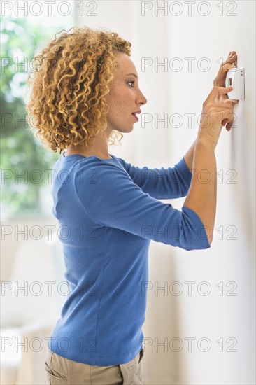 Young woman setting air conditioning.