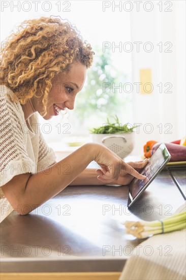 Young woman using digital tablet in kitchen.