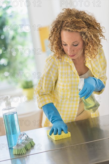 Young woman cleaning in kitchen.