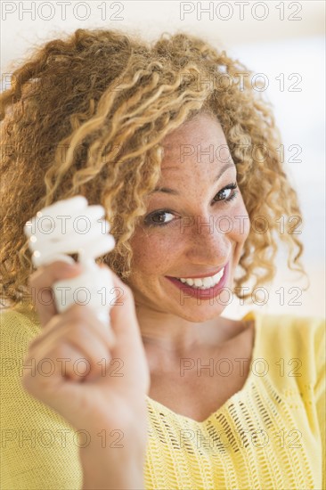 Portrait of smiling young woman holding light bulb.