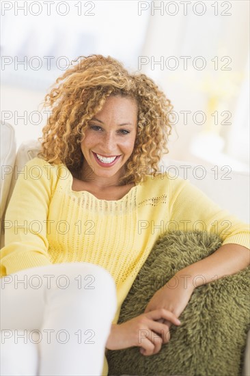 Portrait of smiling young woman sitting on sofa.
