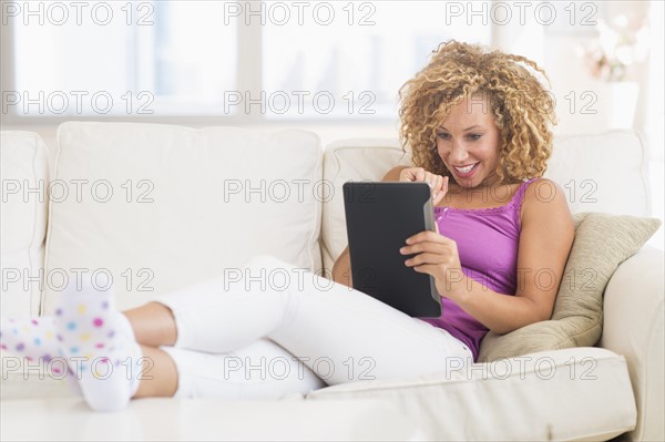 Young woman sitting on sofa with digital tablet.