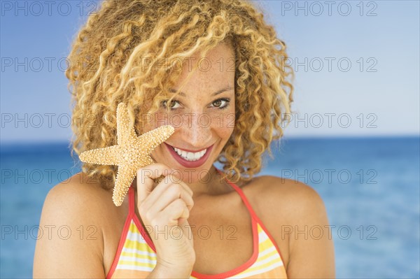 Portrait of young woman holding starfish.
