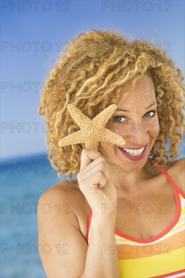 Portrait of young woman holding starfish.