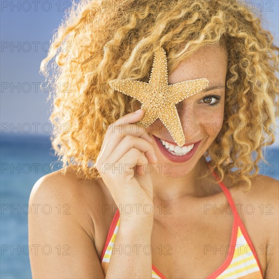 Portrait of young woman holding starfish.