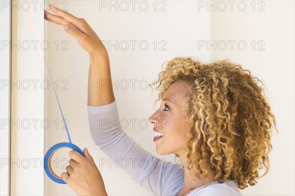 Young woman applying duct tape on wall.