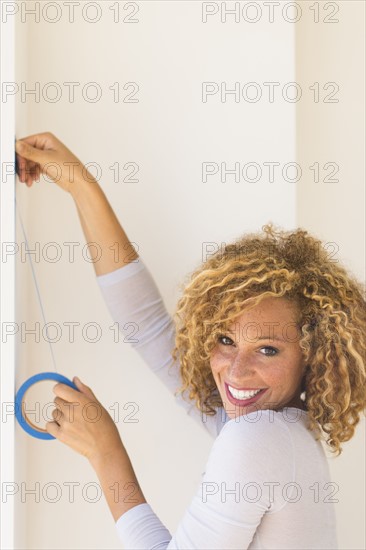 Young woman applying duct tape on wall.