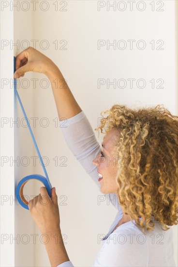 Young woman applying duct tape on wall.