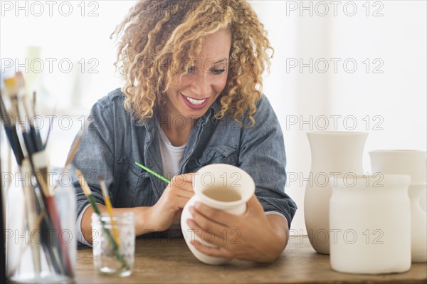 Female artist painting on ceramics in studio.