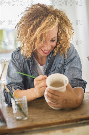 Female artist painting on ceramics in studio.