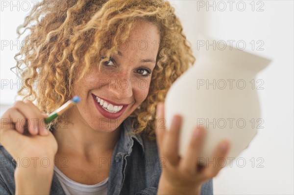 Portrait of female artist painting on ceramics in studio.