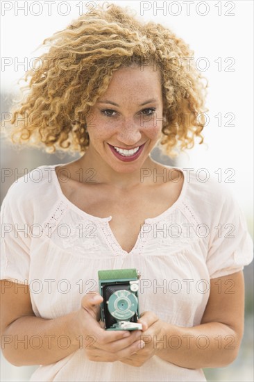 Portrait of young woman holding camera.