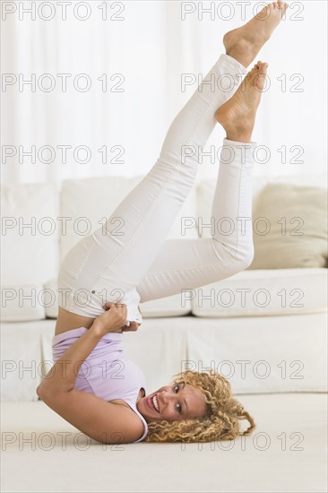 Young woman trying on tight jeans on the floor.