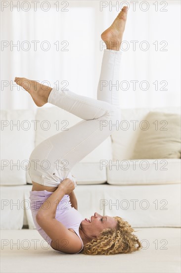 Young woman trying on tight jeans on the floor.