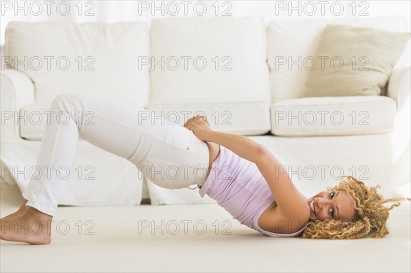 Young woman trying on tight jeans on the floor.