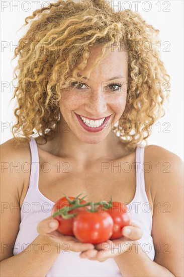 Portrait of young woman holding tomatoes.