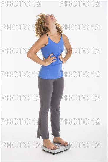 Young woman standing on weight scale, studio shot.