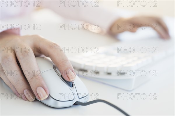 Close up of woman's hands using computer keyboard and computer mouse.