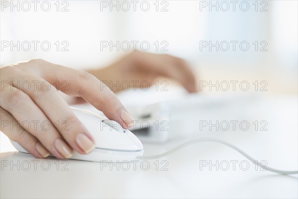 Close up of woman's hands using computer keyboard and computer mouse.