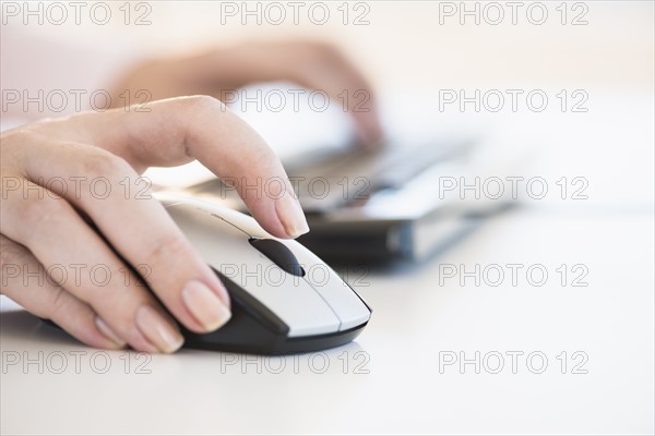 Close up of woman's hands using computer keyboard and computer mouse.