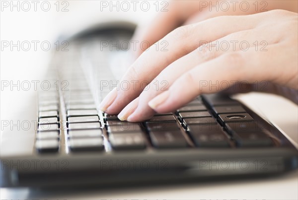 Close up of woman's hands typing on computer keyboard .