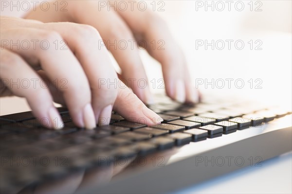 Close up of woman's hands typing on computer keyboard .