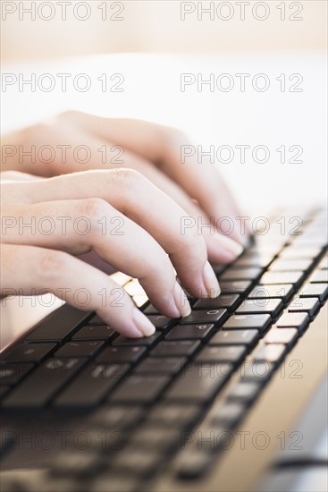 Close up of woman's hands typing on computer keyboard .