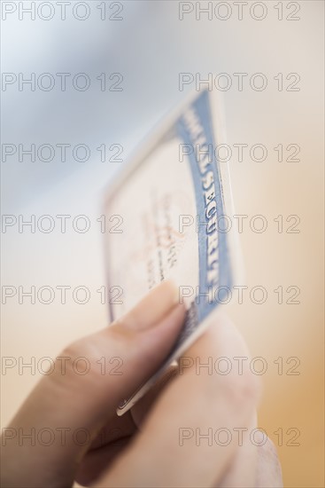 Close up of woman's hand holding social security card.