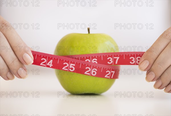 Woman measuring green apple.