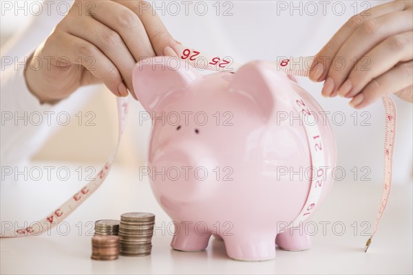 Woman measuring piggybank.