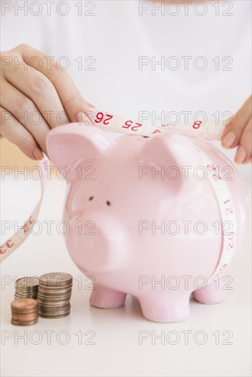 Woman measuring piggybank.