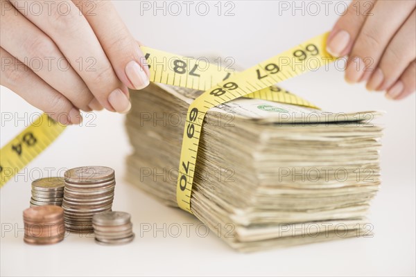 Woman measuring bunch of banknotes.