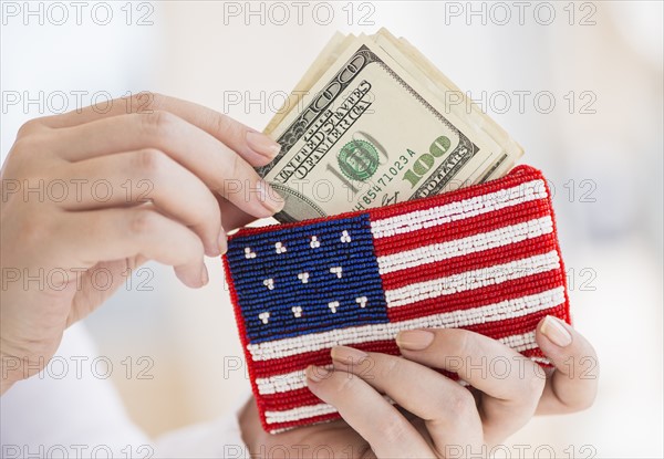 Woman holding banknotes and purse with american flag on it.