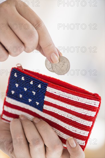Woman holding coins and purse with american flag on it.