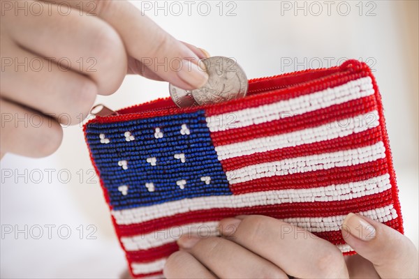 Woman holding coins and purse with american flag on it.