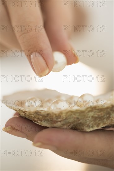 Woman holding shell and pearl.