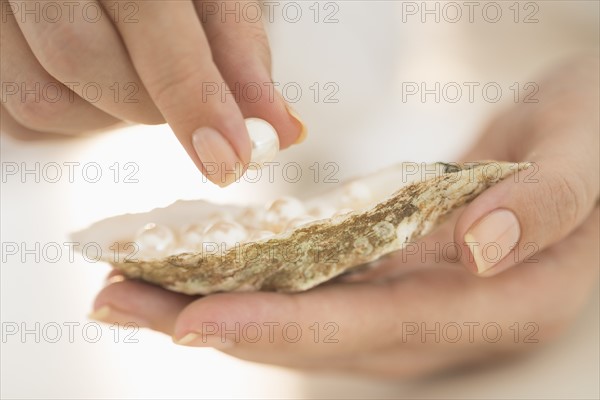 Woman holding shell and pearl.