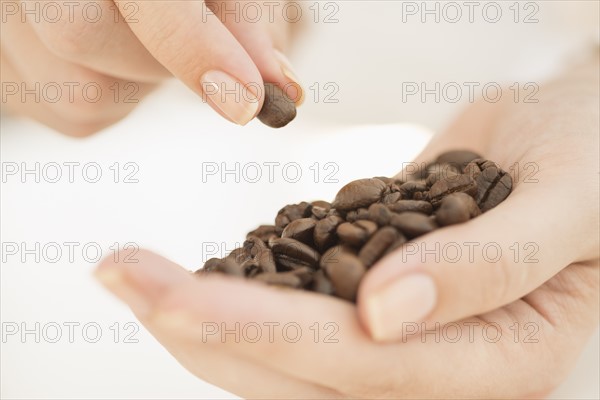 Coffee beans on woman's hand.