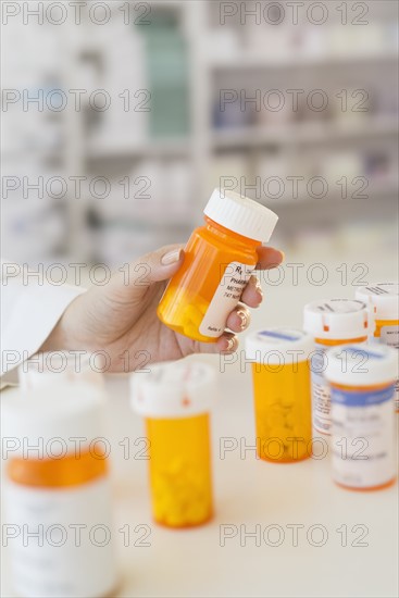 Pharmacist holding pill bottle.