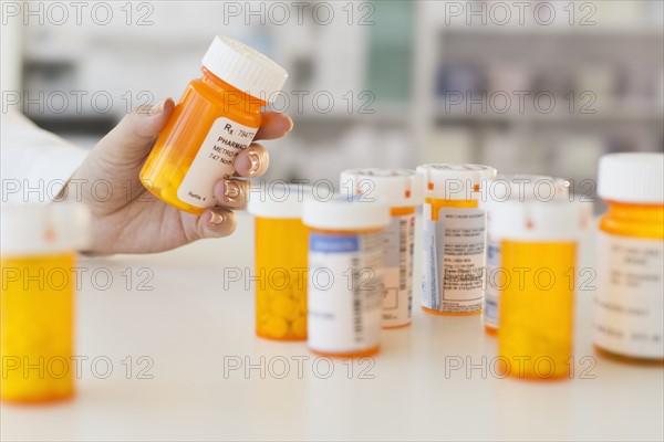Pharmacist holding pill bottle.