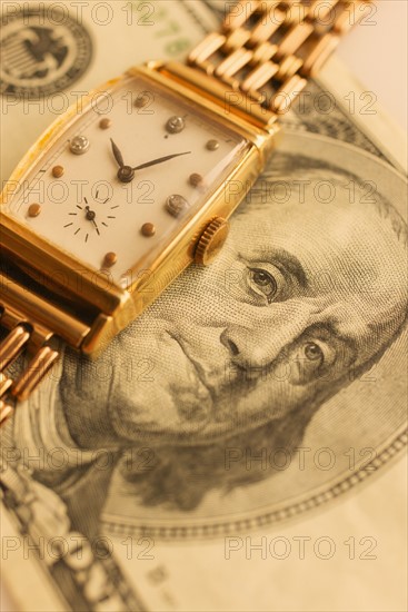 Studio shot of banknote and gold watch.