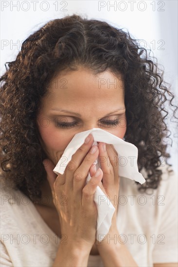 Portrait of woman blowing nose.