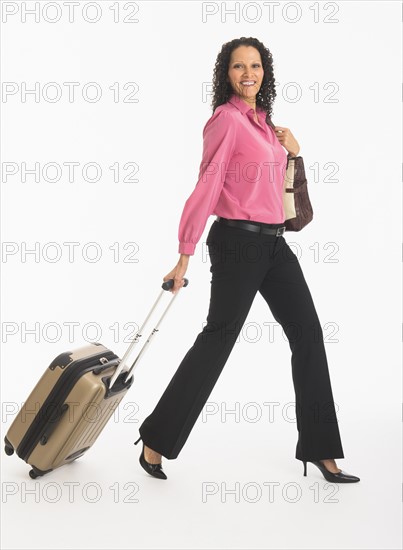 Studio shot of woman walking with suitcase.