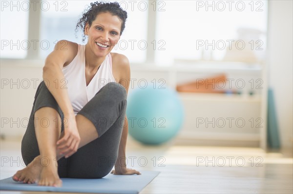 Portrait of woman sitting on exercising mat.