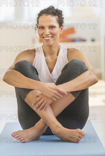 Portrait of woman sitting on exercising mat.