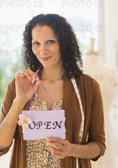 Portrait of woman holding open sign.