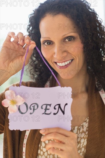 Portrait of woman holding open sign.